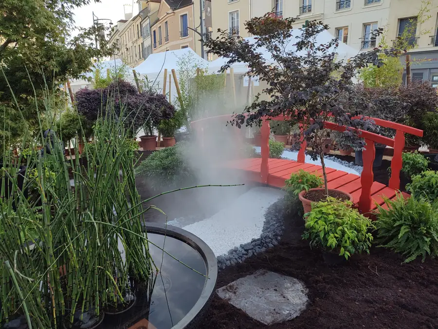 Jardin éphémère installé sur une place de centre-ville, avec brume au-dessus du bassin