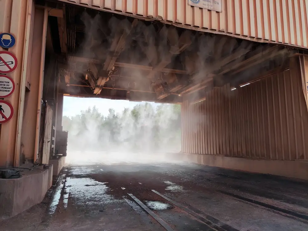 Rampes de buses sous une trémie de chargement, brume dense au passage des camions